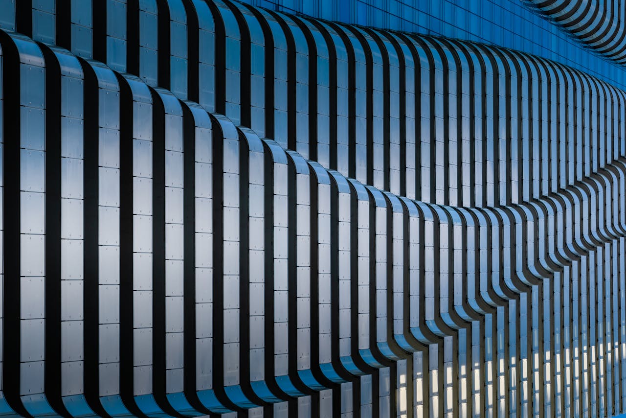 Close-up of a modern building facade featuring wave-like metallic structures and a monochromatic color scheme.